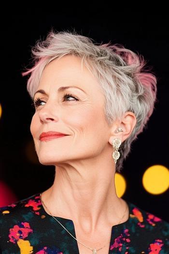 A woman with short, textured, silver hair styled in a chic, messy pixie cut.