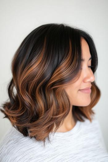 A woman with shoulder-length, wavy black hair accented with warm brown highlights.