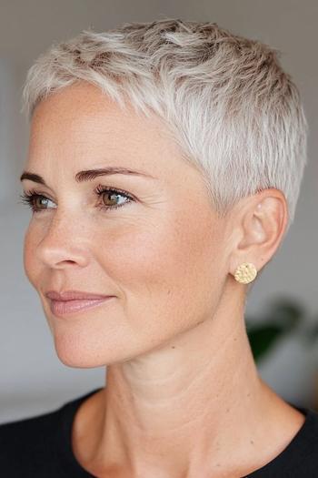 A woman with a short, pixie haircut featuring textured layers and a natural grey color.