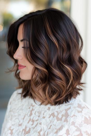 A woman with shoulder-length wavy black hair featuring subtle brown highlights.